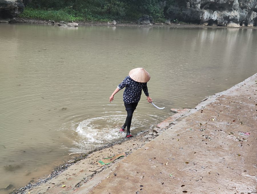 cestovanie vo Vietname v tradicnom klobuku v dazdi