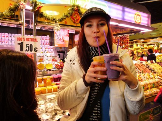 crazy sexy fun traveler drinking fruit juices in la Boqueria market in Barcelona