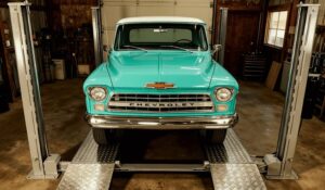 Classic teal Chevrolet pickup truck on a hydraulic garage lift