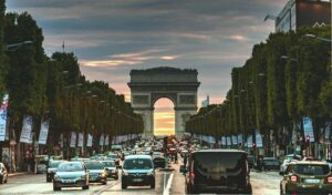 A vibrant view of the Arc de Triomphe in Paris with bustling traffic at sunset